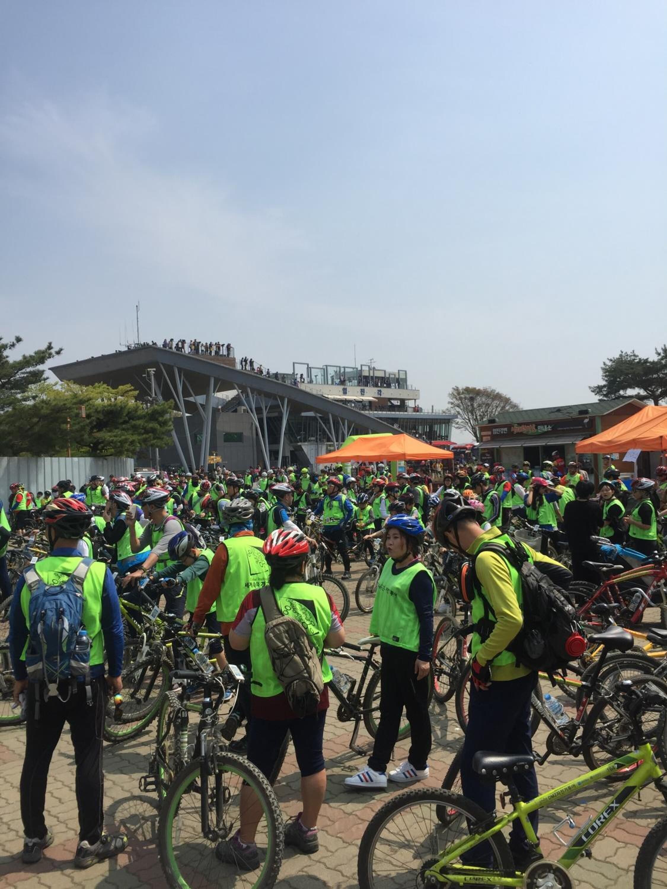 A group of people with bicycles gathered outdoors, some wearing safety vests.