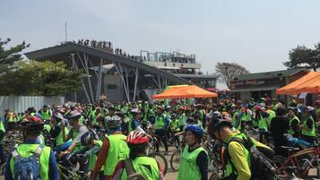 A group of people with bicycles gathered outdoors, some wearing safety vests.
