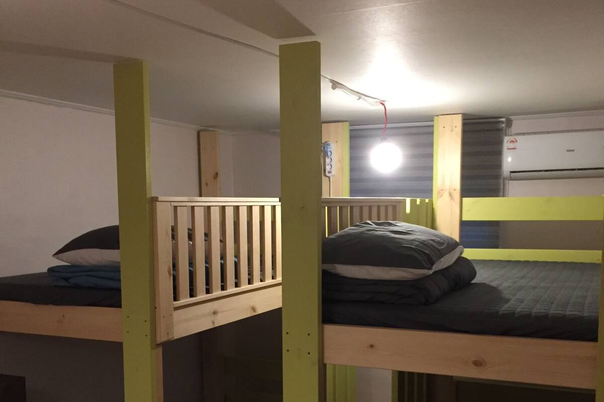 A bunk bed room with wooden frames and green accents.