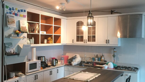 A modern kitchen with white cabinets, a wooden island, and a hanging light fixture.