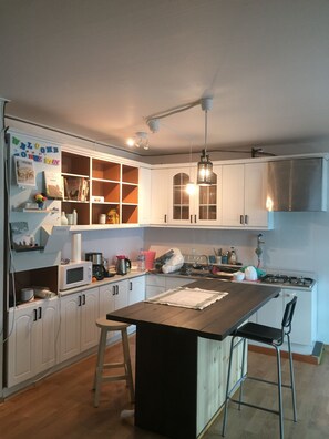 A modern kitchen with white cabinets, a wooden island, and a hanging light fixture. - The Guesthouse DMZ Stay - Hostel (Paju)