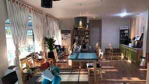 A spacious living room with a dining area, a bookshelf, and a kitchen area.