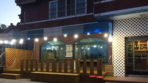 A building with a wooden deck, outdoor seating, and a large window.