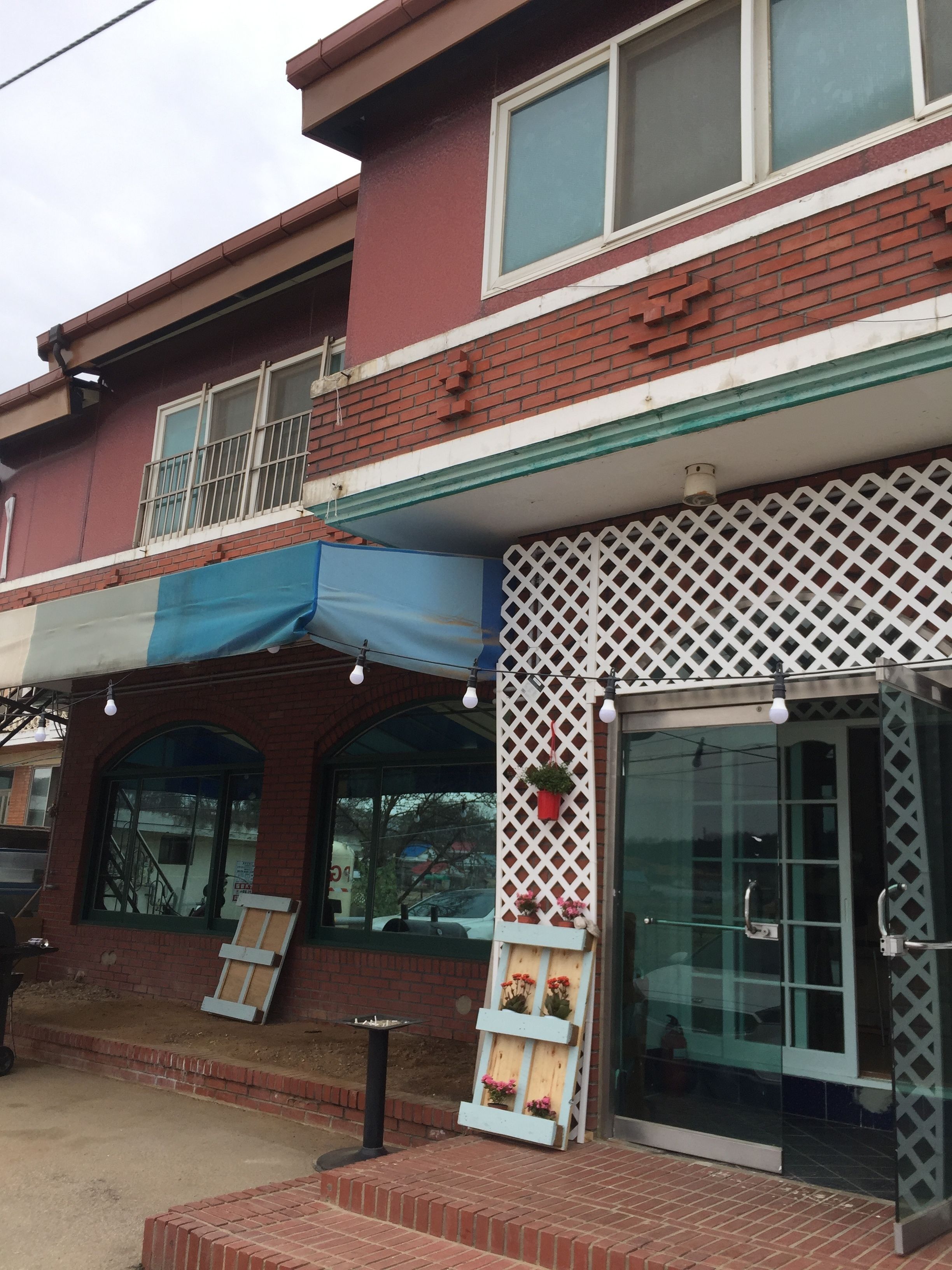 A building with a red brick facade, a blue awning, and a glass entrance.
