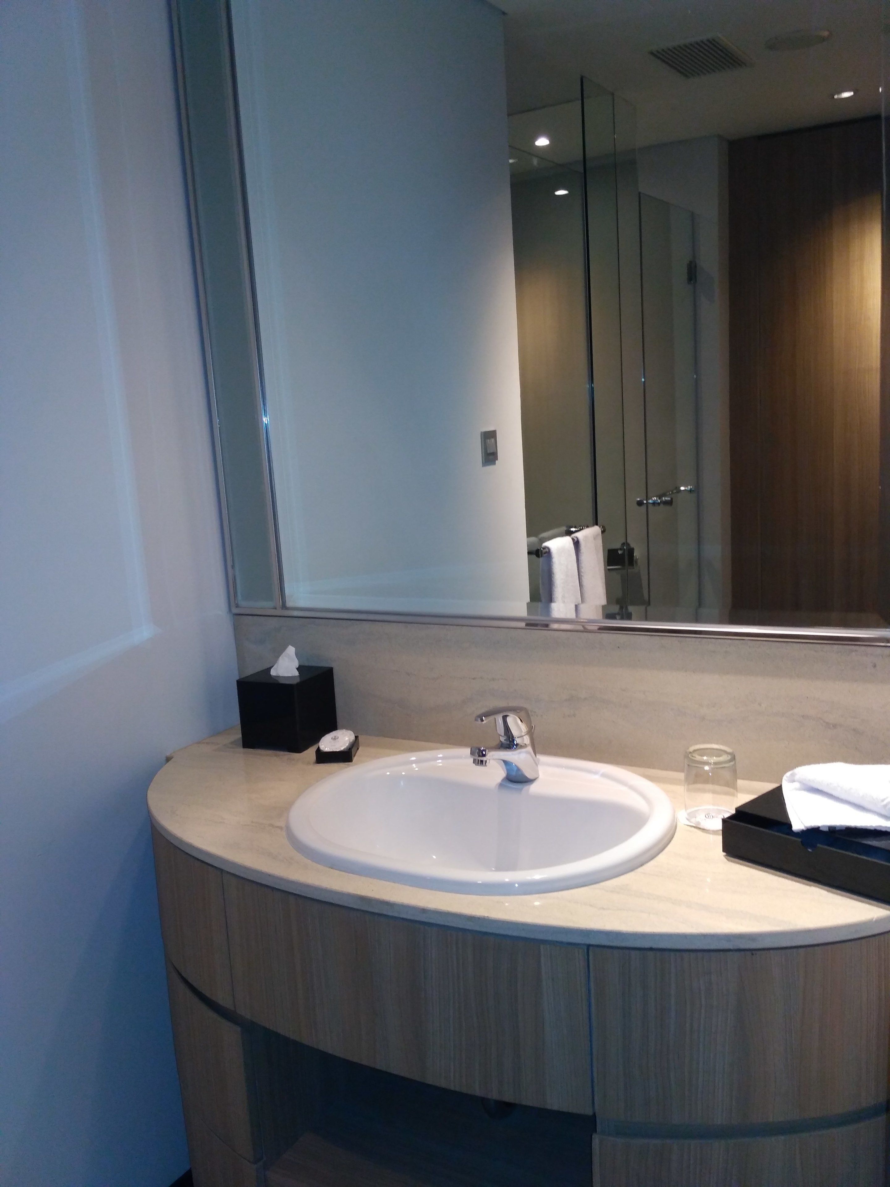 Un baño moderno con un lavamanos redondo, un espejo y una cabina de ducha de vidrio.