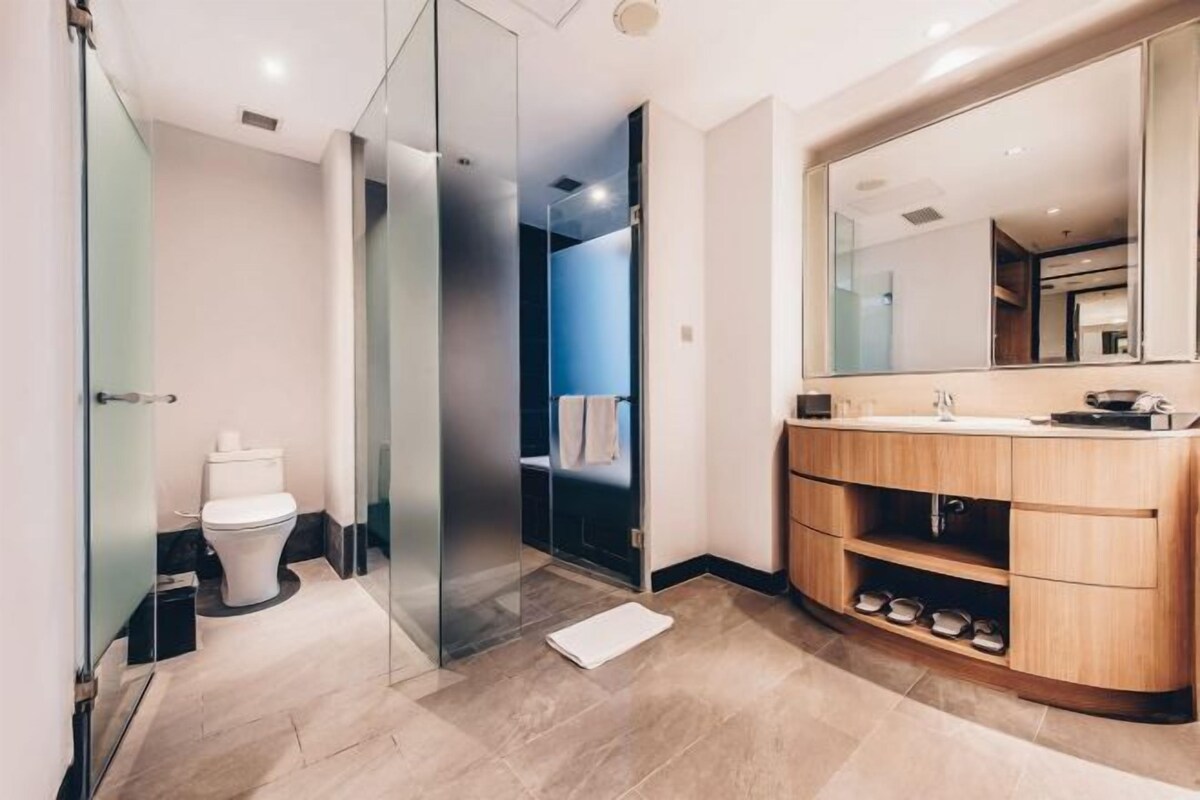 Un bagno moderno con cabina doccia in vetro, un water e un mobile bagno in legno con uno specchio grande.