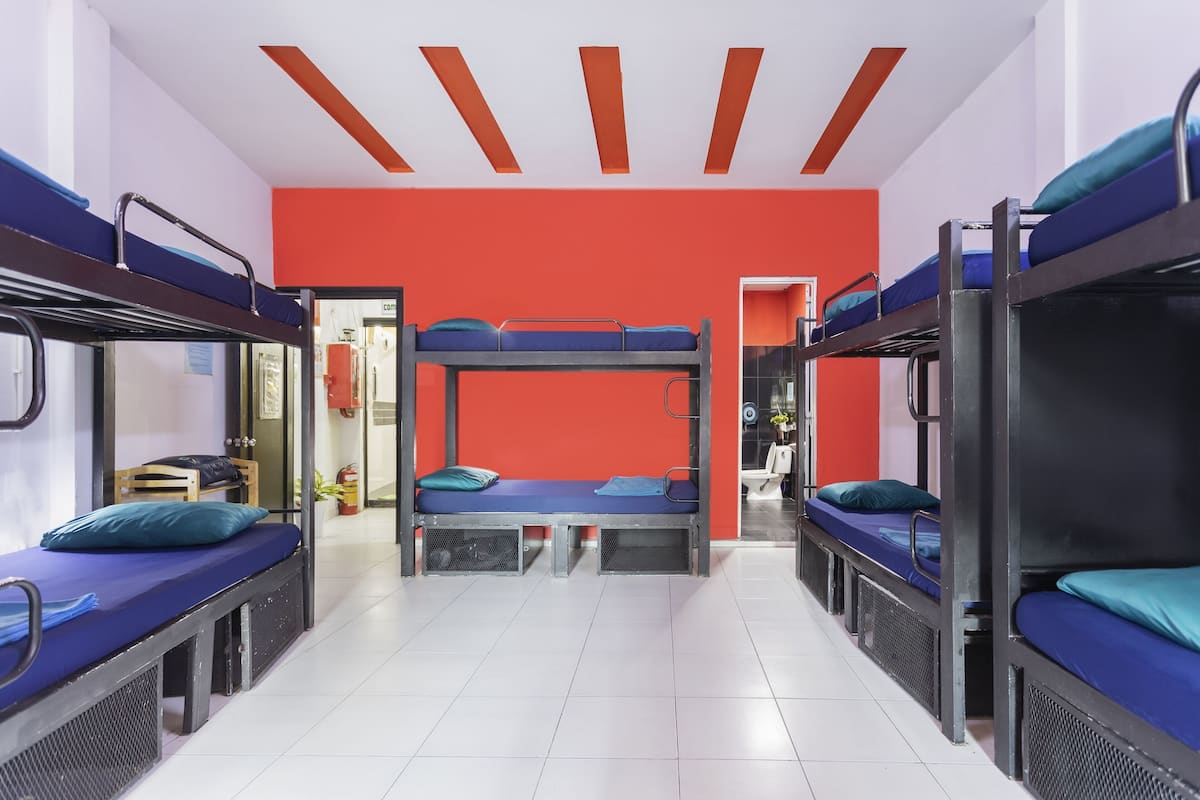 Quarto de dormitório com beliches, parede com detalhes em vermelho e piso de azulejos brancos.
