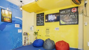 Una habitación con paredes coloridas, pufs, carteles motivacionales y una planta pequeña.
