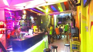 Zona de bar con mostrador, taburetes y una persona sirviendo detrás.