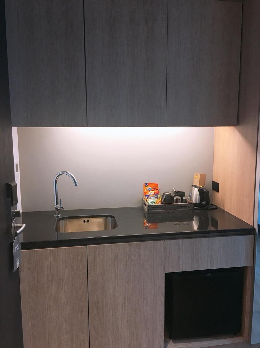 A modern kitchen with a stainless steel sink, a coffee maker, and a box of cereal on the counter.