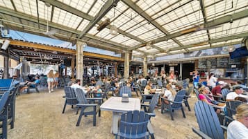 Un espace de restauration en plein air, avec des tables et des chaises, un toit abrité et une vue sur la rue.