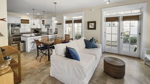 Un espacio habitable amplio con un sofá blanco, una mesa de comedor y una cocina al fondo.