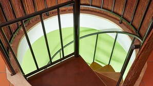 A spiral staircase with a green and brown color scheme, metal railings, and a bamboo-like wall. - CORAL VILLA, a charming landscape close to the beach, best choice for families (Carvoeira)