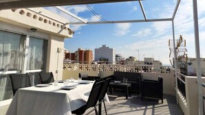 A rooftop terrace with tables and chairs, a view of the cityscape, and a covered area with a railing. - Apartment with terrace just 250 m from the beach (Torre Del Mar)