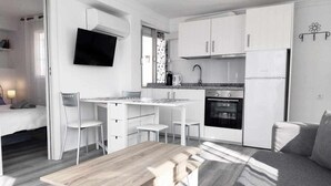 A compact, modern apartment with a kitchenette, a dining area, and a living space. - Apartment with terrace just 250 m from the beach (Torre Del Mar)