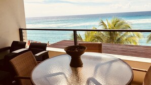 A balcony with a round table and wicker chairs, overlooking a beach with palm trees and the ocean. -  Sunset Beach - Ocean front with stunning sea views, WI-FI, AC. (Oistins)