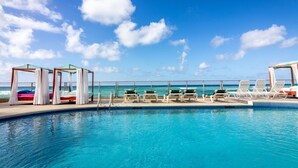 A poolside area with lounge chairs and a pool, overlooking the ocean. -  Sunset Beach - Ocean front with stunning sea views, WI-FI, AC. (Oistins)
