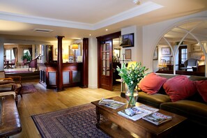 A spacious living room with a wooden coffee table, a sofa, and a dining area with a table and chairs. - The Royal Hotel (Crieff)