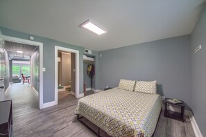 A bedroom with a bed, a nightstand, and a door leading to another room.