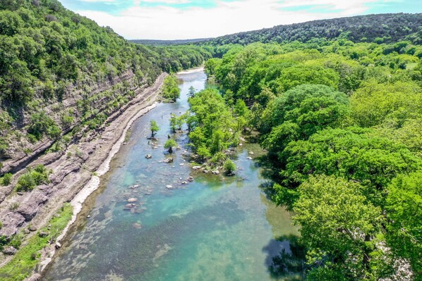 A river flowing through a forested valley with rocky terrain on one side and dense greenery on the other.