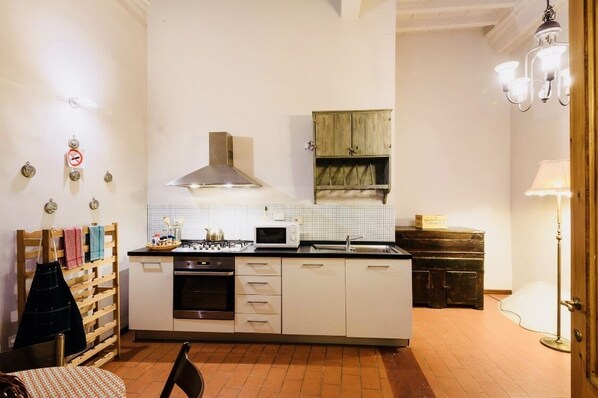 Una cocina compacta con armarios blancos, un microondas, una estufa y un mueble de madera.