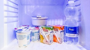 Un réfrigérateur contenant divers aliments, notamment des yaourts, des briques de jus de fruits et une bouteille d’eau.