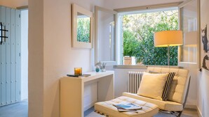 Habitación moderna con sofá blanco, una mesita, una lámpara y vistas a zonas verdes.