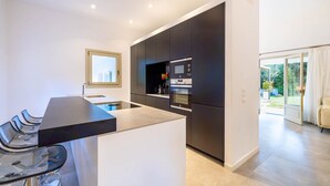 Una cocina moderna con una isla central, horno empotrado y una ventana sobre el fregadero.