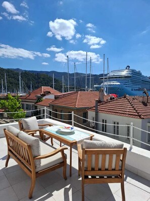 Un balcon agrémenté de meubles en bois, une vue sur un navire de croisière et un paysage montagneux.