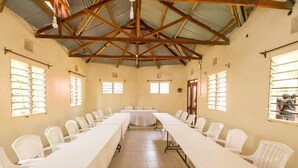 A conference room with a long table and chairs, a high ceiling with wooden beams, and windows with bars. - Legacy 2014 Hotel (Bondo)