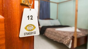 A room with a bunk bed, a wooden door, and a keychain with a room number. - Legacy 2014 Hotel (Bondo)