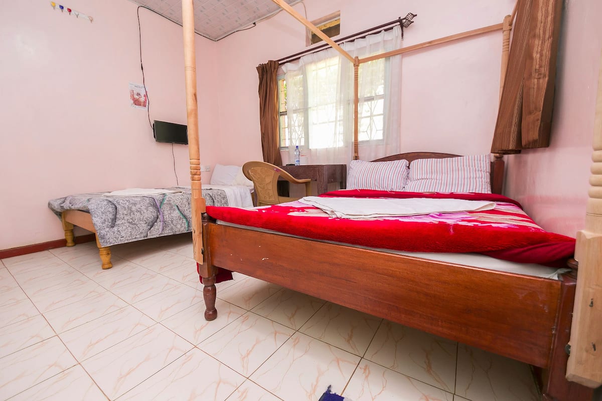 Quarto com cama de madeira, cama adicional, escrivaninha e cadeira.