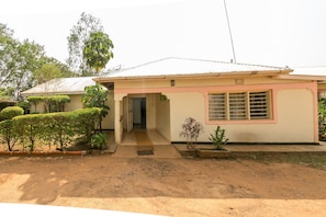 A single-story house with a front porch, a small garden, and a dirt driveway. - Legacy 2014 Hotel (Bondo)