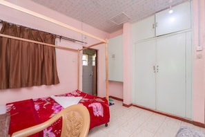 A bedroom with a bed, wardrobe, and a chair. - Legacy 2014 Hotel (Bondo)