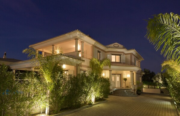 Une maison à deux étages avec un balcon, une entrée bien éclairée et une allée pavée.