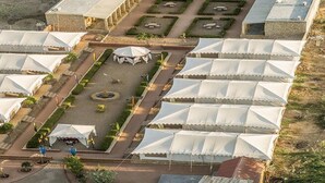Vista aérea de un hotel con varias tiendas de campaña, un patio central y edificios circundantes.