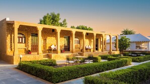 Un edificio tradicional con muros de piedra, varios arcos y un patio con asientos y plantas.