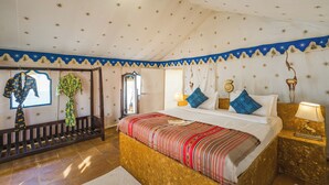 Una habitación de hotel con una cama, mesitas de noche, un banco y un espejo.
