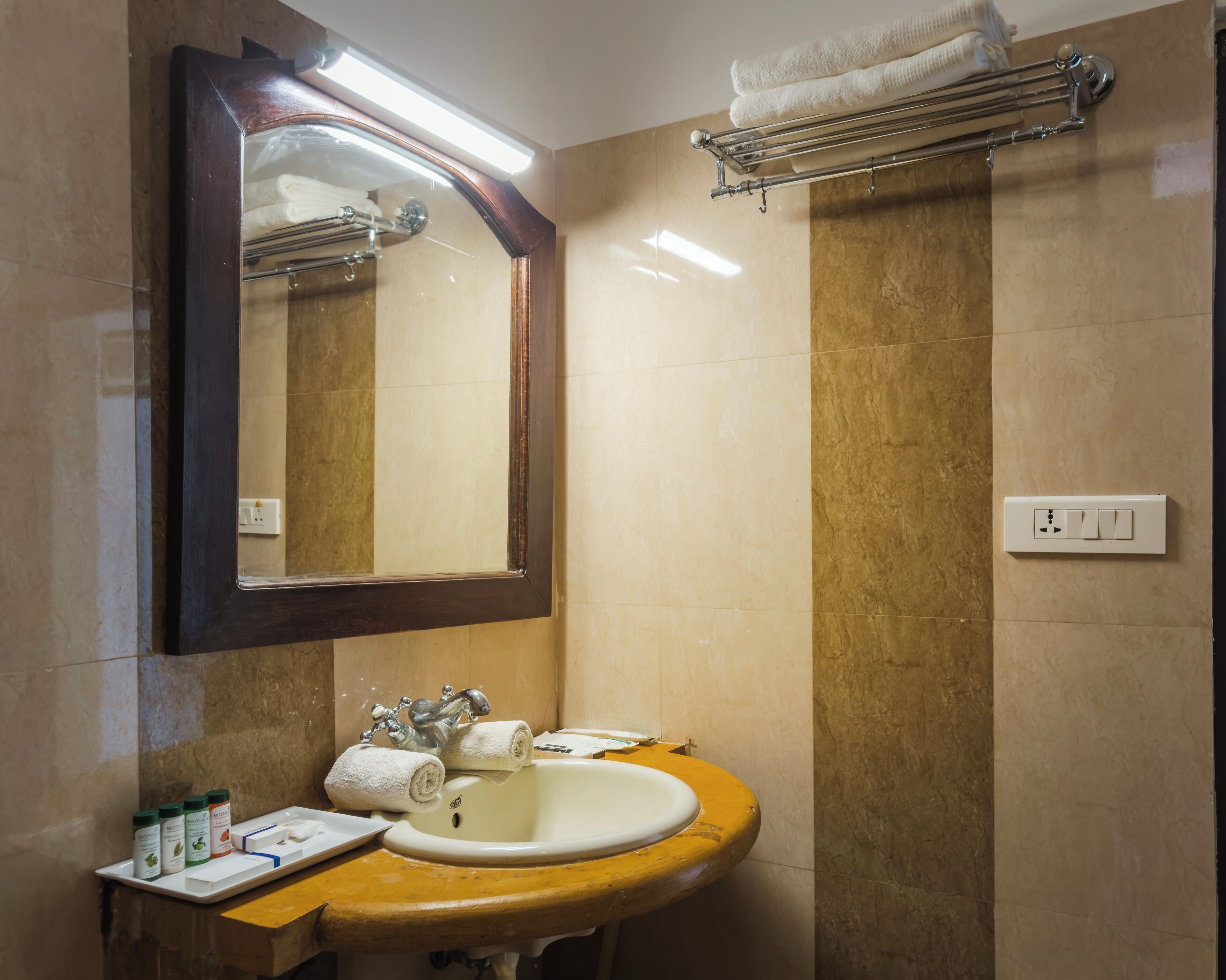 Une salle de bain avec un meuble-lavabo en bois, un lavabo blanc, un miroir et un porte-serviettes.