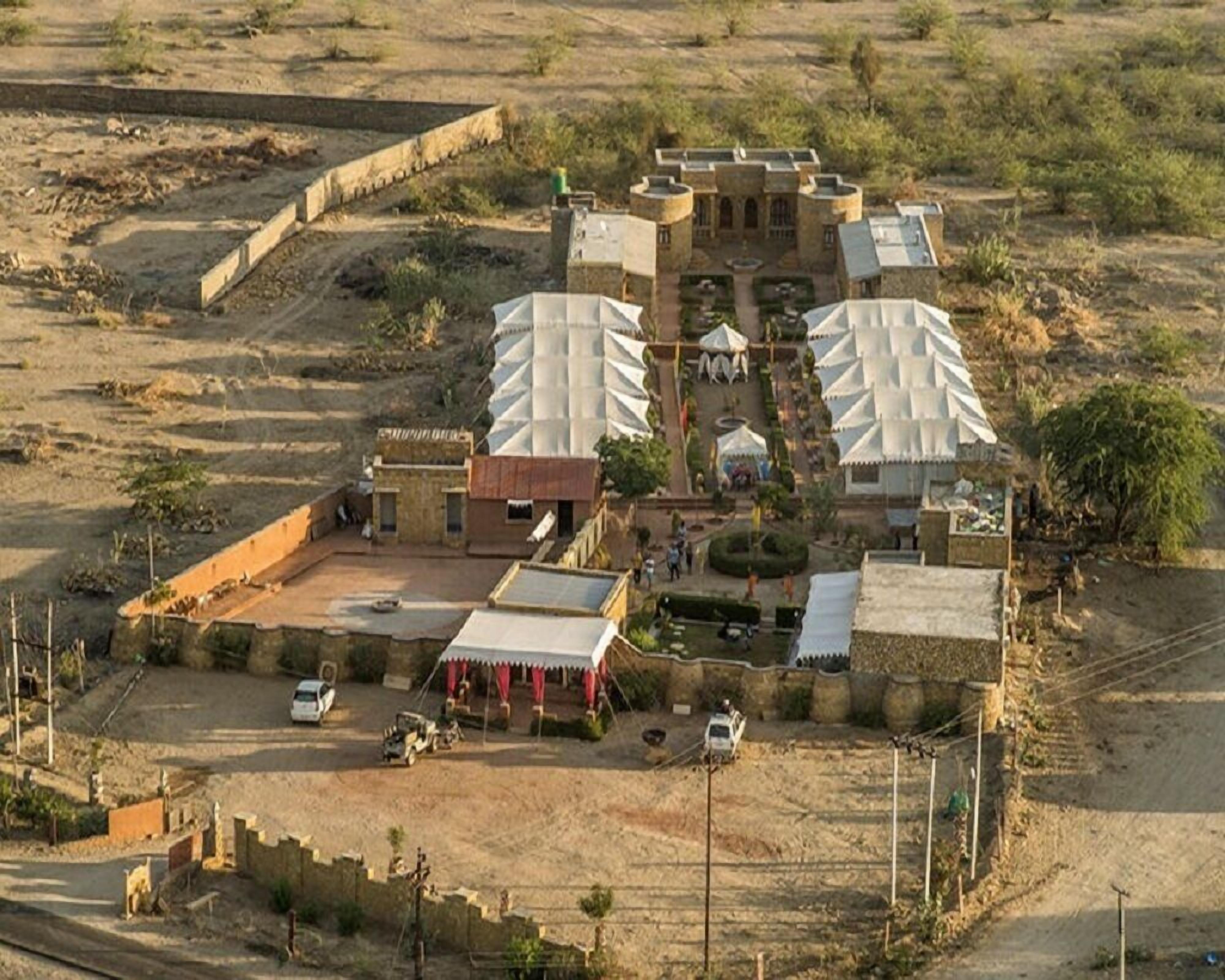 Un resort en el desierto con un edificio central que cuenta con un patio, rodeado de tiendas y caravanas.
