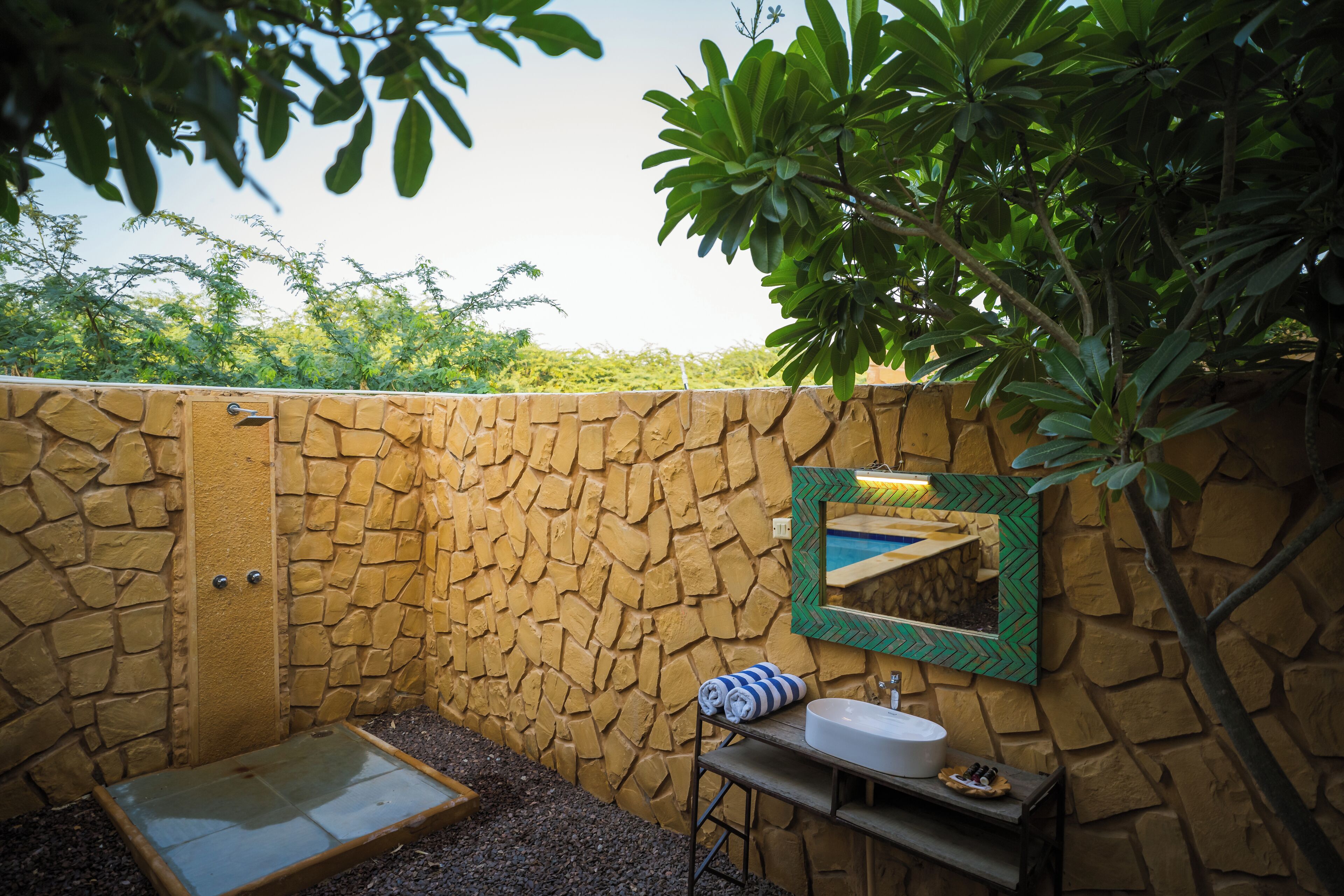 A stone-walled bathroom with a sink, mirror, and shower.