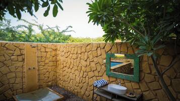A stone-walled bathroom with a sink, mirror, and shower.