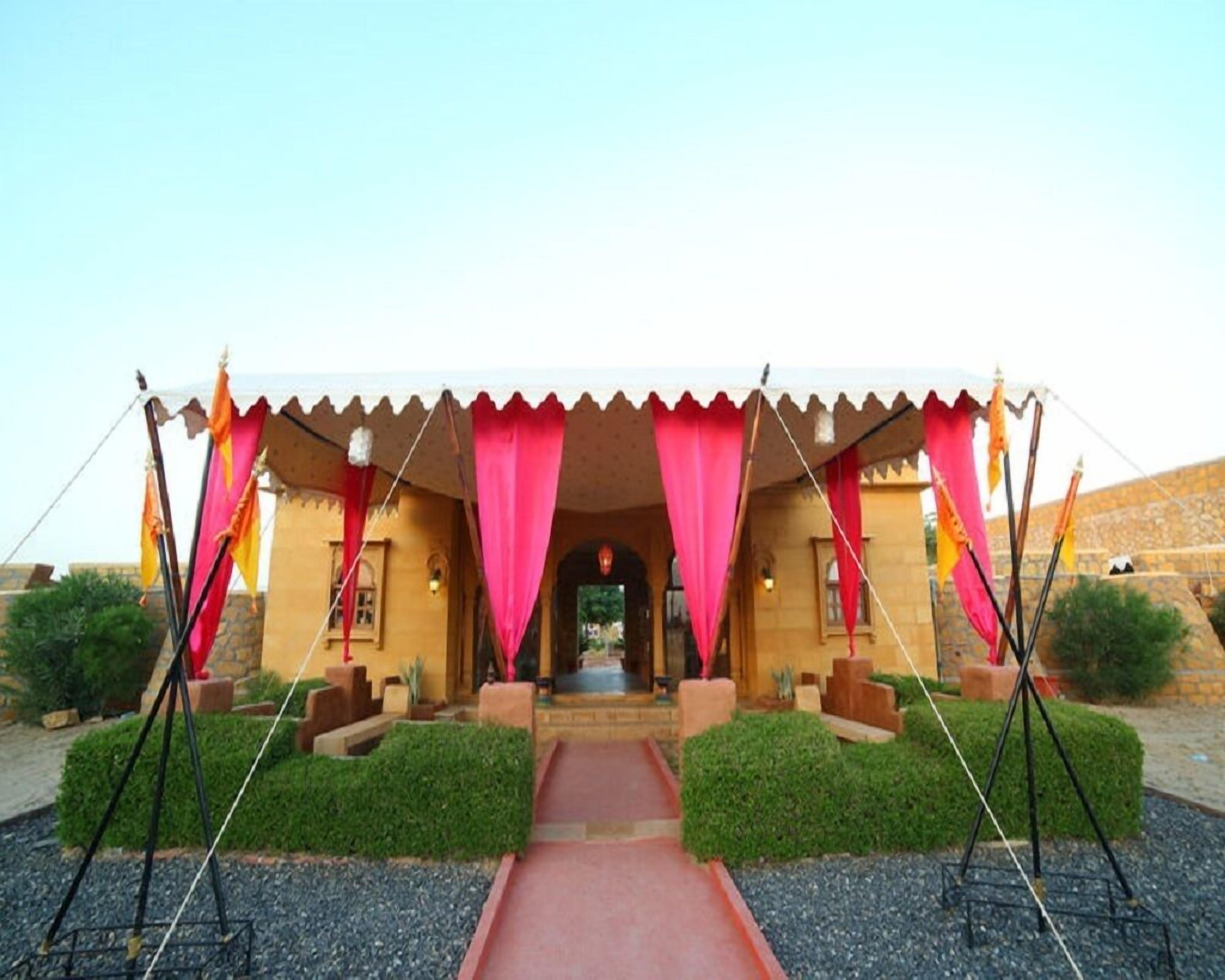 Un edificio tradicional con entrada roja, rodeado de vegetación y un muro de piedra.