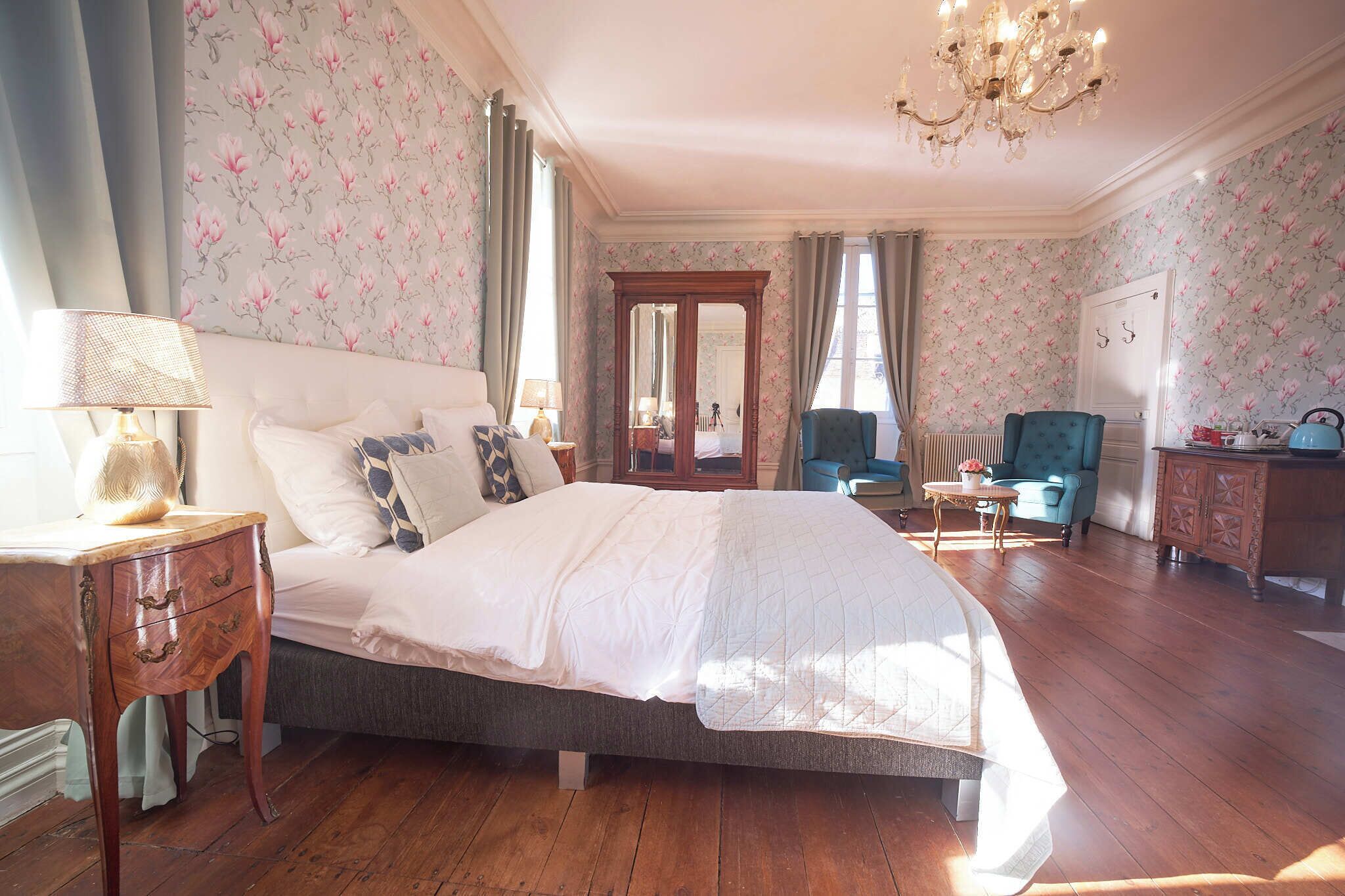 A bedroom with a large bed, a dresser, a chair, and a table.