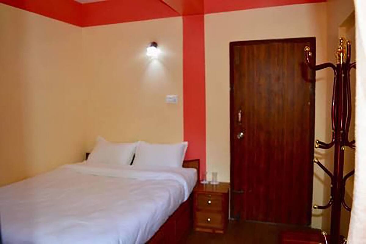 A bedroom with a bed, a wooden door, and a nightstand.