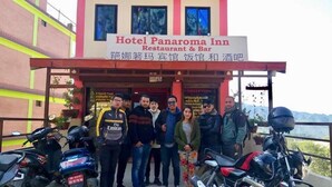 Un groupe de personnes se tient devant l’hôtel Panaroma Inn, qui abrite également un restaurant et un bar.