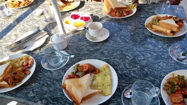 Una mesa de mármol con diversos platos para el desayuno, como tostadas, huevos y fruta.