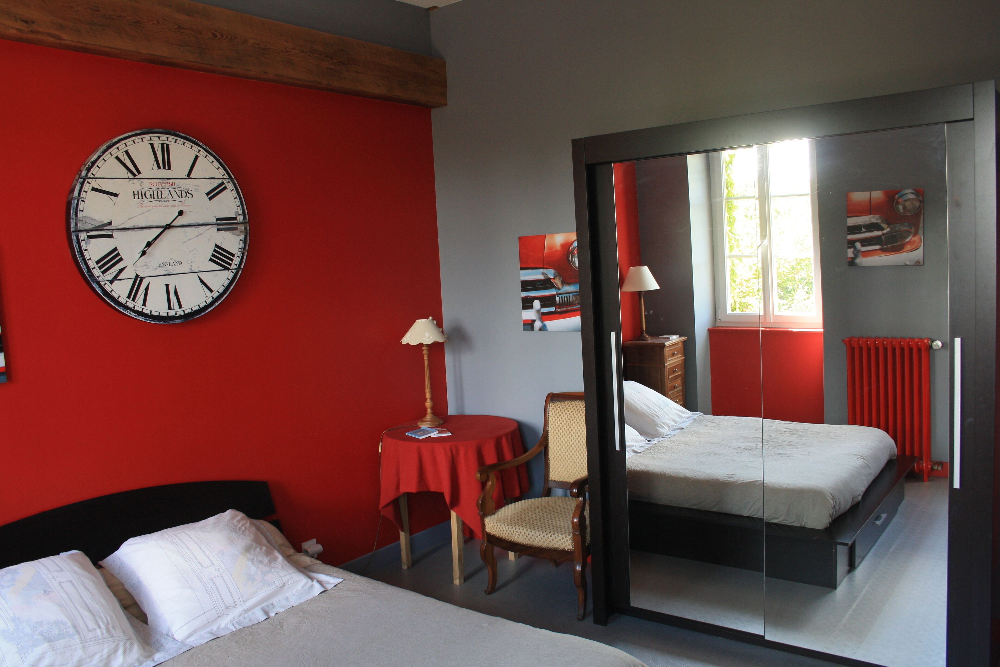 Una habitación de hotel con cama, una silla, una mesa, un reloj y un espejo.