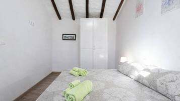 Un dormitorio con cama, armario, un cuadro en la pared y ventana.