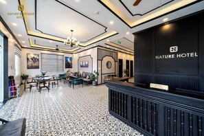 A hotel lobby with a reception desk, seating area, and a patterned floor.
